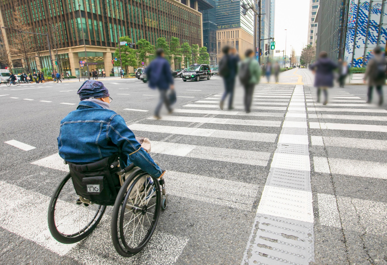 写真：車いす使用者が点字ブロックのある歩道をまっすぐ移動する様子