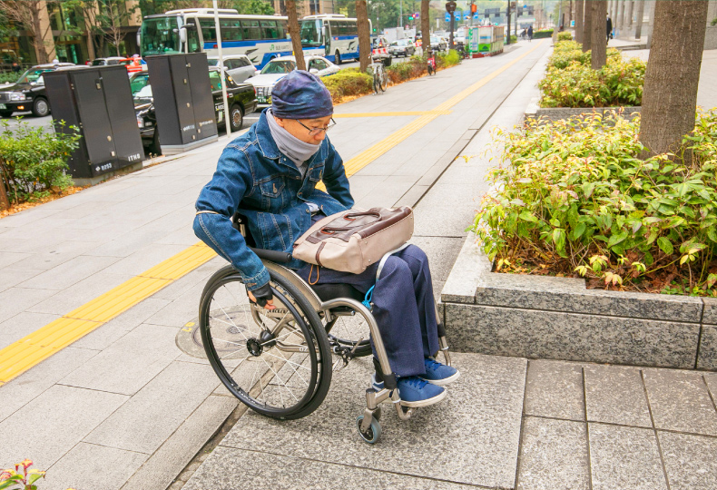 写真：車いす使用者が歩道からビル横のスロープに移動する様子