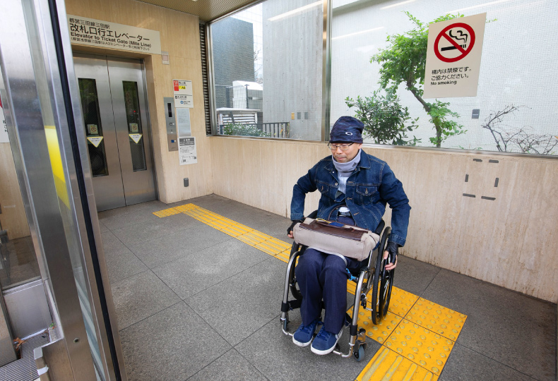 写真：車いす使用者がエレベーターホールから屋外へ移動する様子
