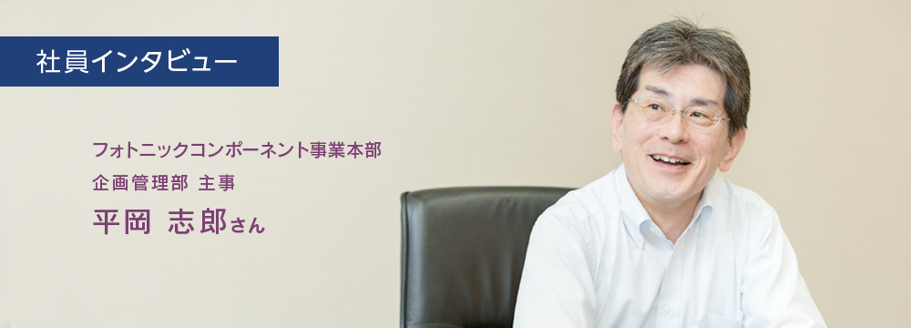 社員インタビュー　フォトニックコンポーネント事業本部　企画管理部　主事　平岡志郎さんのインタビューのバストショット。笑顔でインタビューに答えている様子。