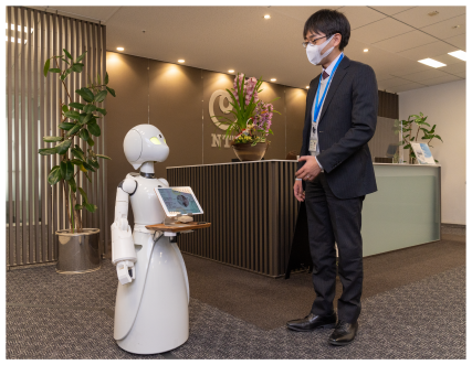 写真：人型の分身ロボットと男性が視線を合わせて会話をしている様子
