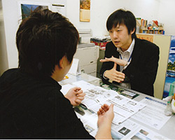 写真:片桐さんがカウンター席で旅行のパンフレットを見ながら手話でお客様に対応している様子。