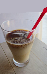 写真：くちの広い透明グラスに7分程注がれているミルクと飲むアイスコーヒーゼリーに赤いストローが付いています