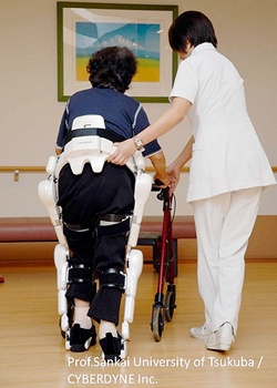 写真：両脚型を装着し介護を受けながら歩行訓練を行っている様子