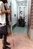 写真：高尾山駅のエレベーターへ入る二人の様子