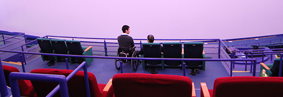 写真：プラネタリウムの座席に座り前のスクリーンを見ている編集部員達