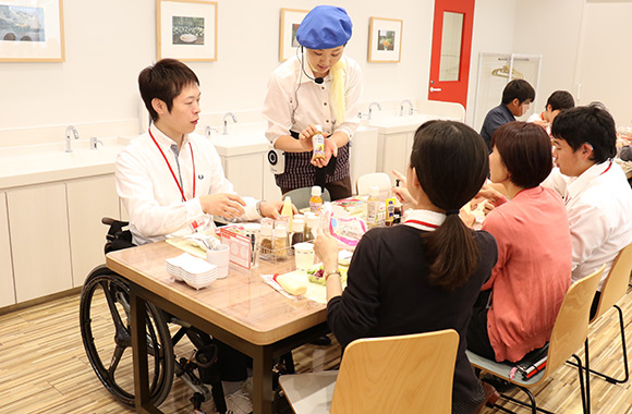 写真：キユーピー キッチンにてマヨネーズソース作り体験をしながらおすすめの食べ方やドレッシングの紹介を受けている様子。