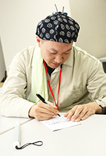 写真：大平さんが歌詞カードにサインをしている様子。