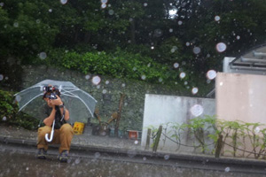 写真：大粒の雨が地面のアスファルトで弾け飛んでいる（しゃがんで撮影、カメラは地面の側-大平さん談）