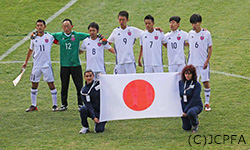 写真：日本チームが日本国旗を前にして肩を組んで整列している所