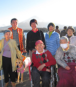 画像：富士山をバックに視覚障がい者と肢体不自由者とサポーターが笑顔でいる様子