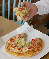 写真：マルゲリータピザを手に取りチーズが伸びている様子