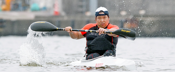 写真：カヌーに乗りカヤックのパドルで水をかく小山選手