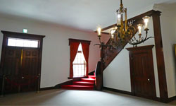 写真：赤いカーペットが敷かれた階段とシャンデリアが写っている様子
