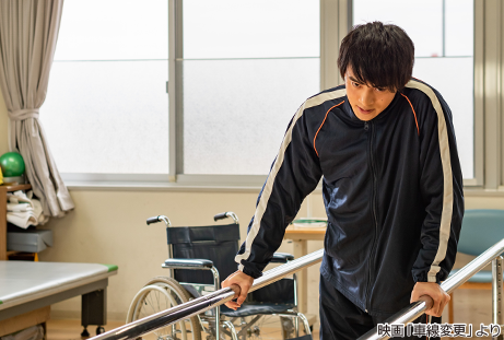 写真：幸助役の平田雄也さんが平行棒でリハビリをしている様子