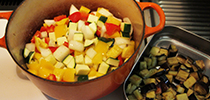 写真：ナスを炒めた鍋でナス以外の野菜をいためている。隣には取り出したナスの入ったプレートが置いてある。