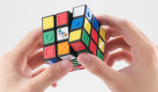 写真：ルービックキューブ ユニバーサルデザインのキューブを回して遊んでる手元のアップ