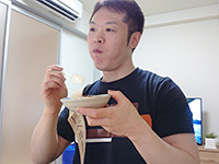 写真：ラー油をかけた冷奴を食べている編集部員