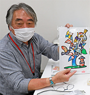 写真：別の編集部員が作ったスミレの切り絵を持ってほほ笑む深川さん