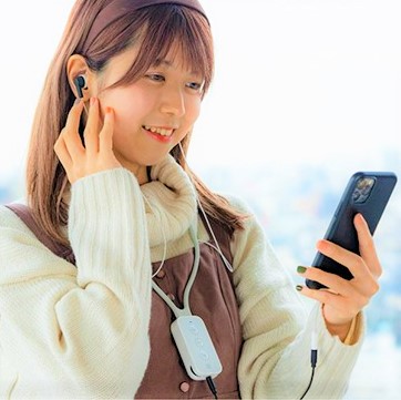 写真：バイボーンネズハイパーをつけた女性がスマートフォンで音楽を聞きながら笑っている