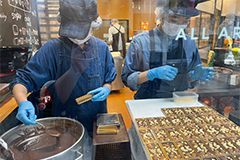 写真：チョコレートを型に流し、その上にナッツなどを乗せている作業風景