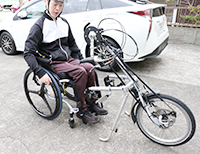 写真：自分の車いすにアダプトタイプの「ハンドサイクル」を一人で取り付けている
