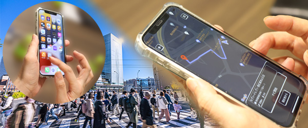 画像：街中をバックにスマートフォンを使って「あしらせ」を操作している