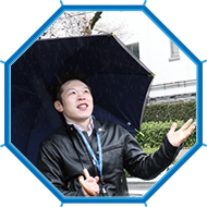 写真：雨の中、車いすユーザの編集部員がサイレントアンブレラを持って雨の様子を伺っている