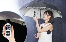 写真：雨の中サイレントアンブレラを差し雨音を計測している女性
