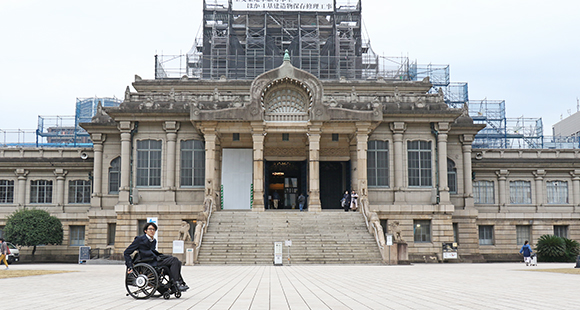 写真：本堂建物の前に車いすユーザがたたずんでいる